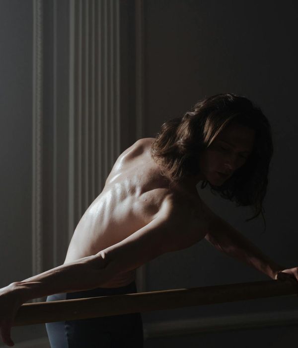 Person practicing gentle balance movements in a dark futuristic studio